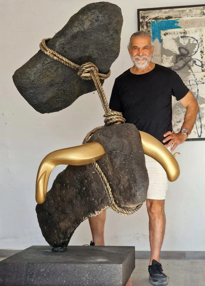 A man behind the bull, in a white room.