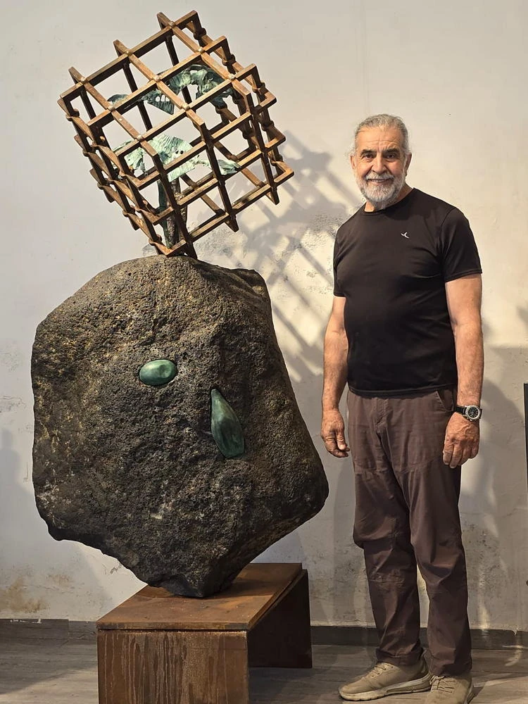 A man beside a basalt boulder crowned with a lattice cube.