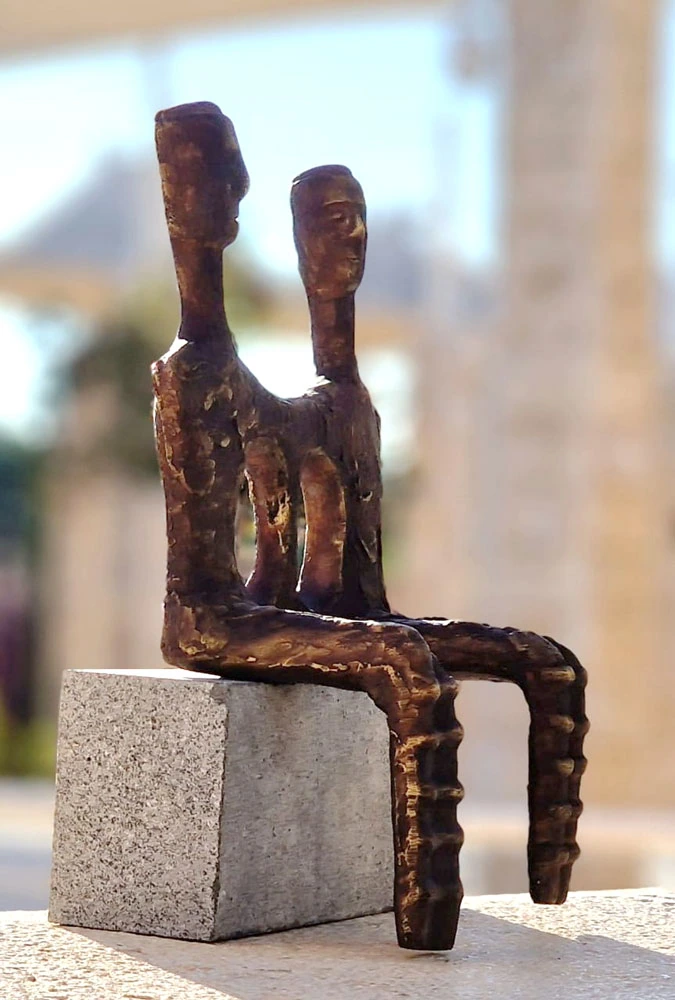 Two seated figures on a pale stone cube.