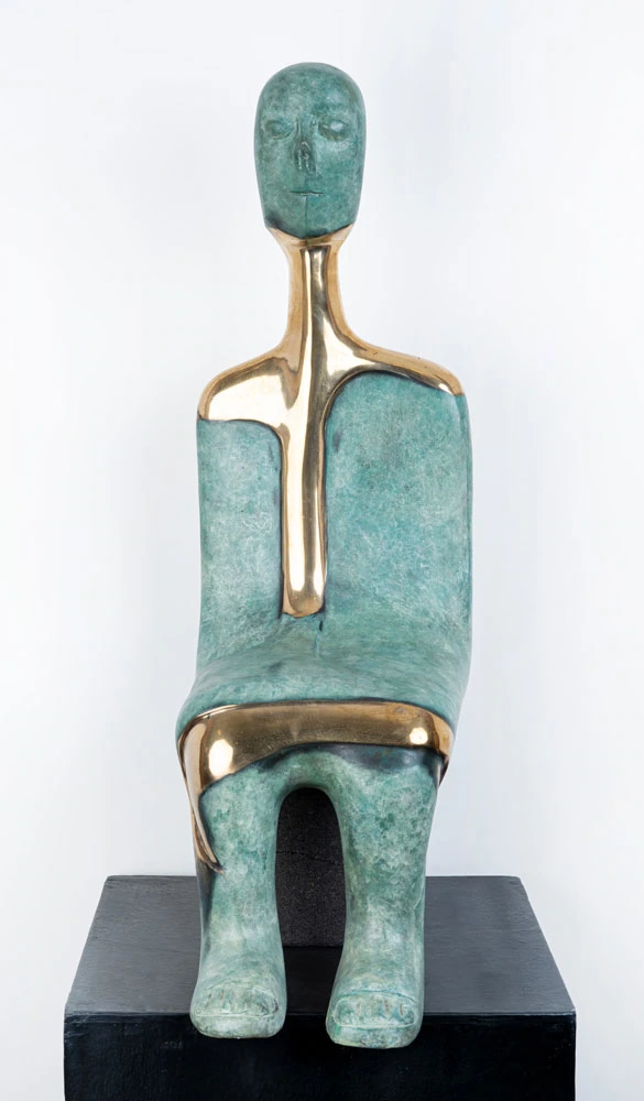 Seated turquoise-patinated figure with polished gold-coloured bands along the neck, chest and lap.