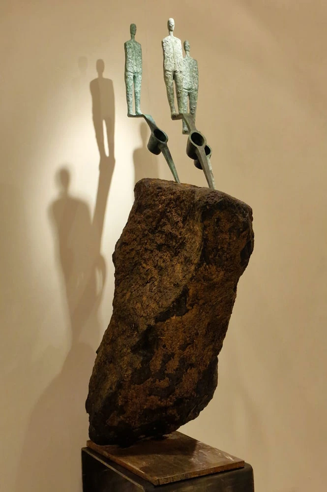 Three standing figures rise above a rock, casting shadows on the wall.