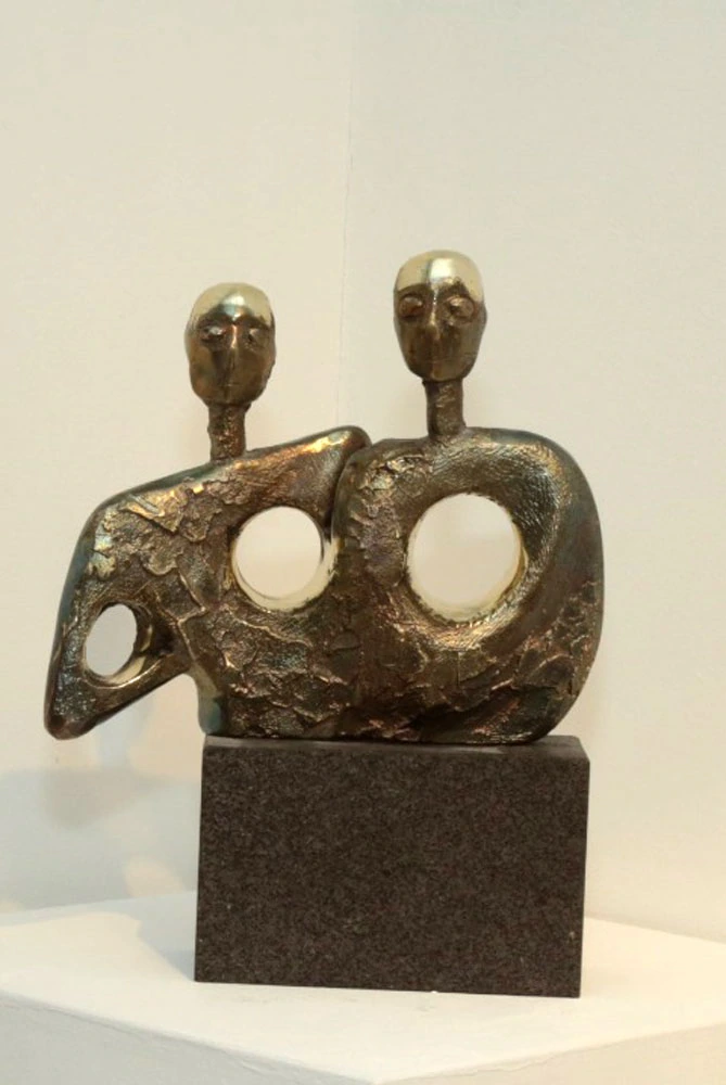 Two joined heads above two circular openings, on a dark base.