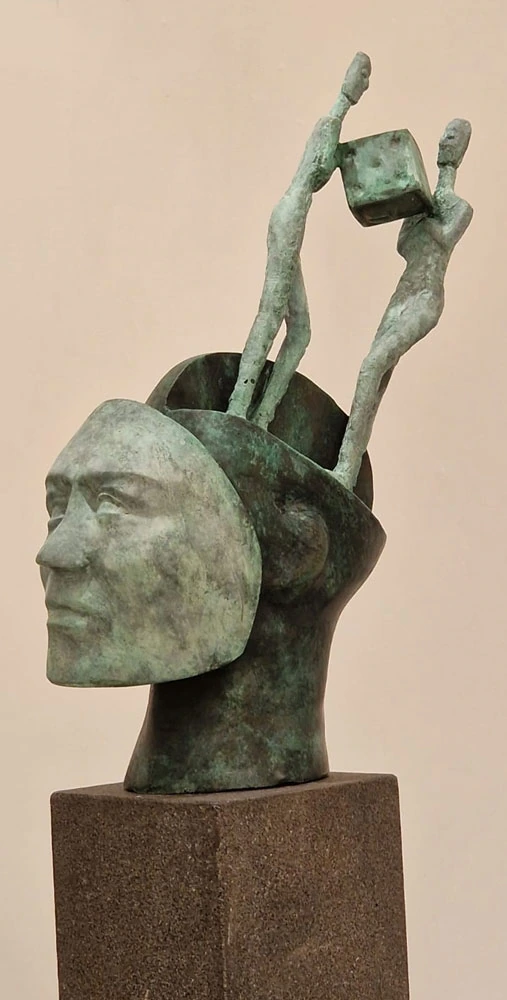 An open head carrying two figures and a cube.