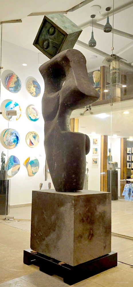 A stone form topped by a die, inside the gallery.