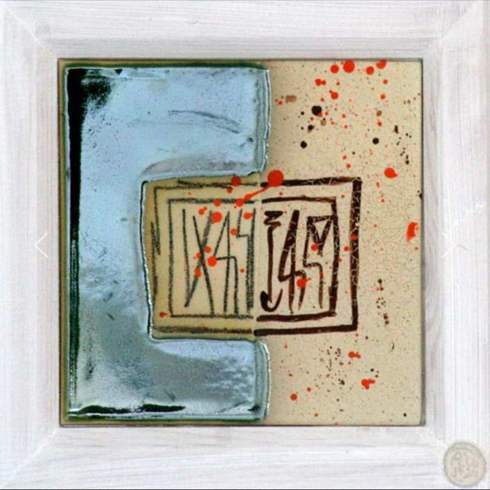 M18: pale blue and cream ceramic panel with a central rectangle of dark signs and scattered red dots.