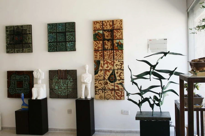 Gallery corner with green ceramic wall panels, pale seated figures and a bronze flock of birds by the window.