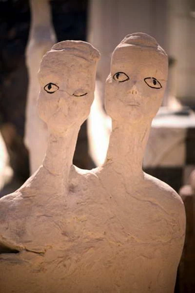 Two heads rising from a single upper body, with eyes drawn in black.