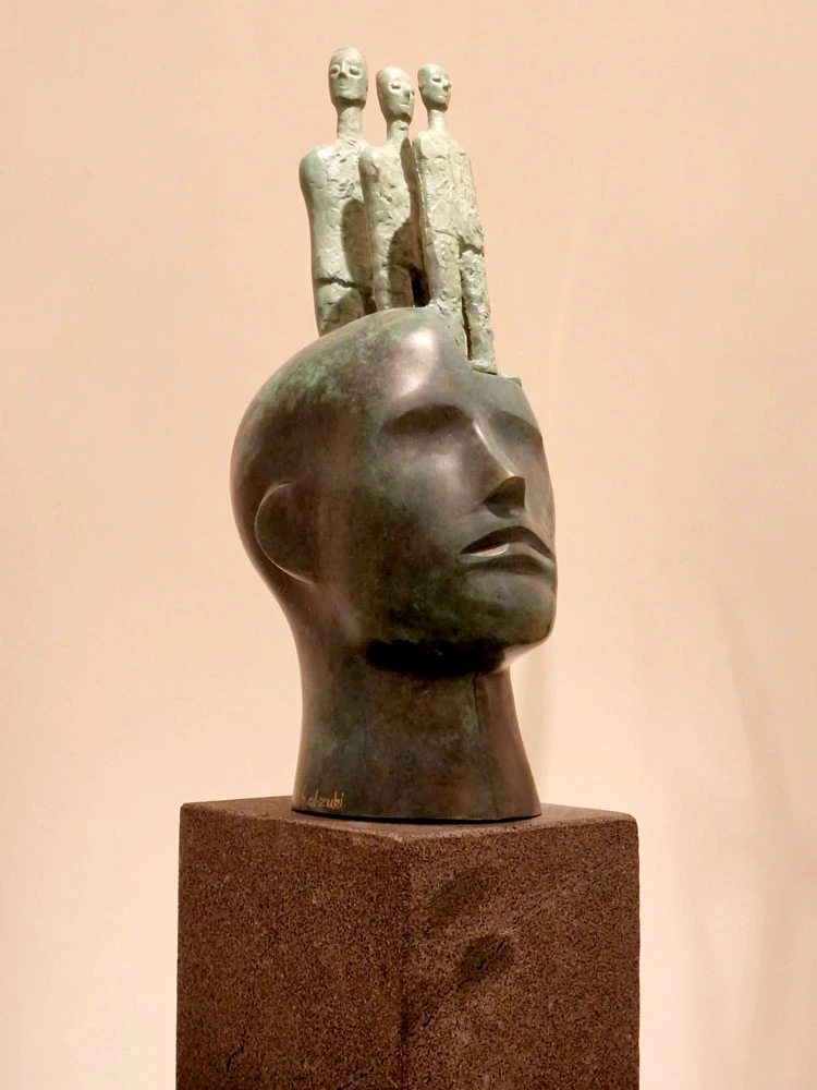Three figures rise above a dark sculpted head.