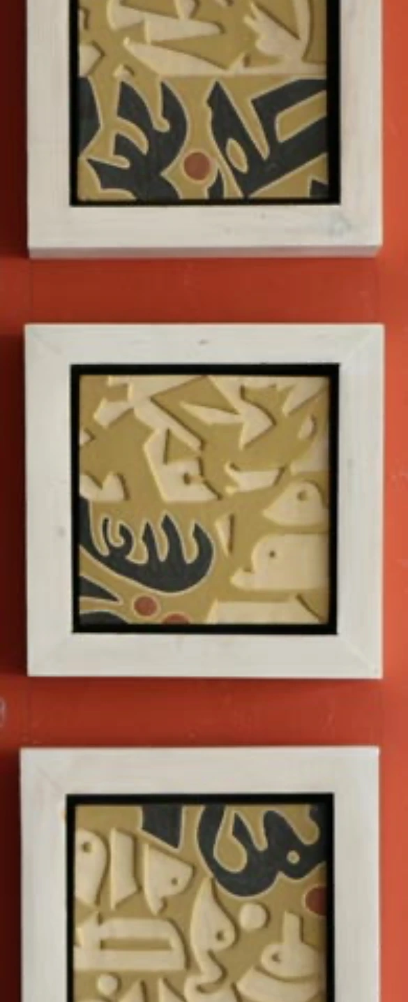 M26: three framed calligraphic ceramic panels stacked vertically against a red wall.