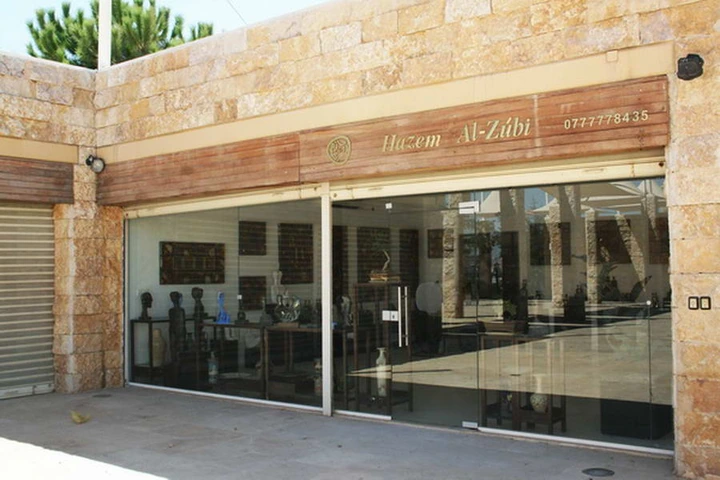 Archival exterior view of Hazem Al-Zubi’s gallery, with its wooden sign and glass-fronted entrance.