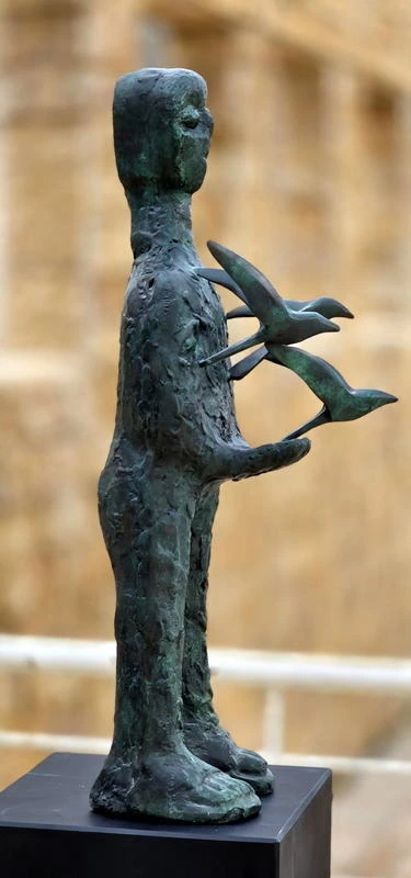 The same figure from the side, the birds fanning out beyond the body.