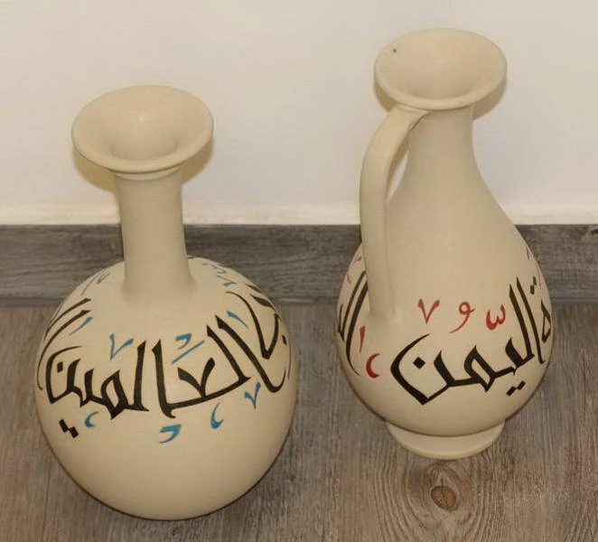 Two cream jars painted with Arabic calligraphy in black with blue and red vowel marks.