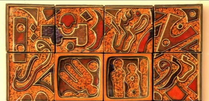 M27: orange ceramic tile composition with raised dark signs, a hand motif and two figures in the centre.