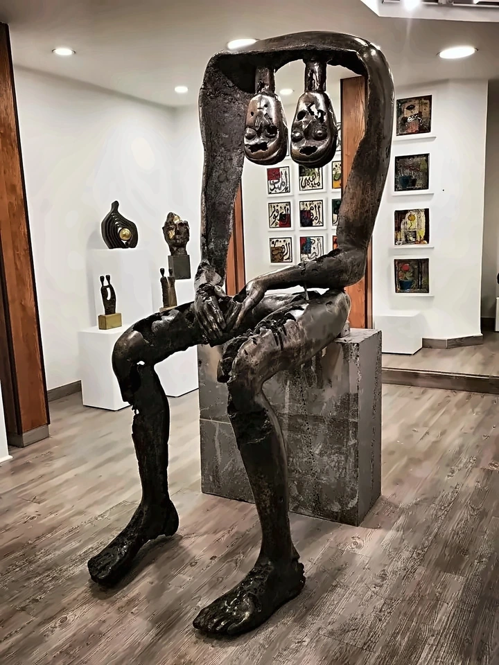 The same figure from the front, its hands folded, feet flat on the gallery floor.