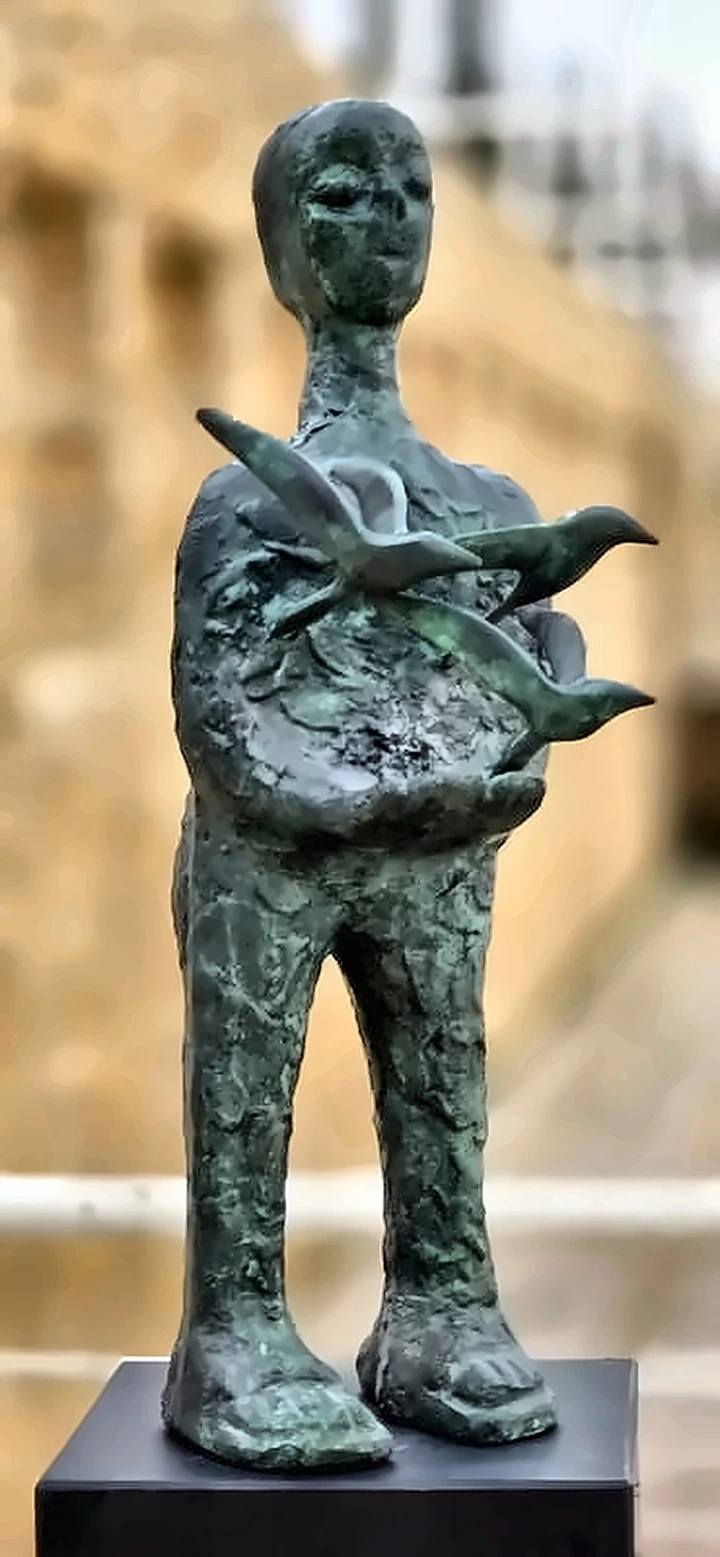 The same figure from the side, the birds fanning out beyond the body.