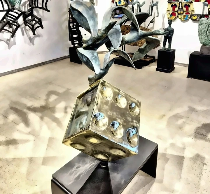 A gilded bronze die on a plinth in the hall, the wall hung with work.