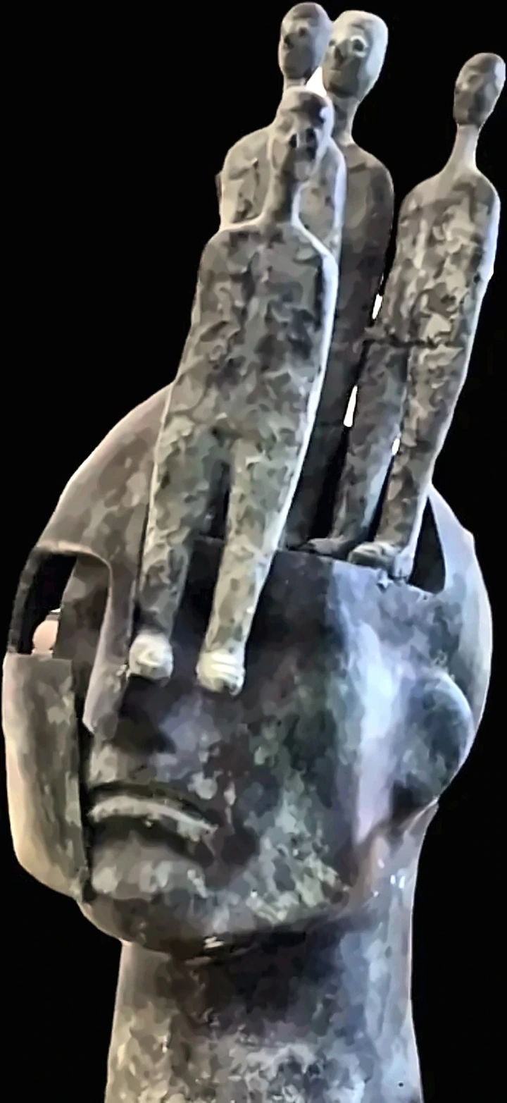 A bronze head opened at the crown with small figures standing out of it.