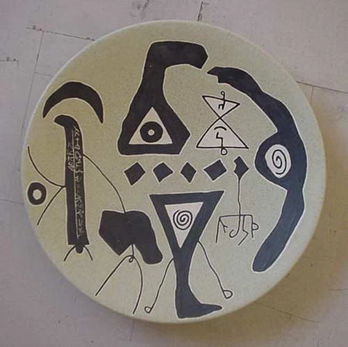 A pale plate with black hooks, triangles, spirals and a row of small diamonds.