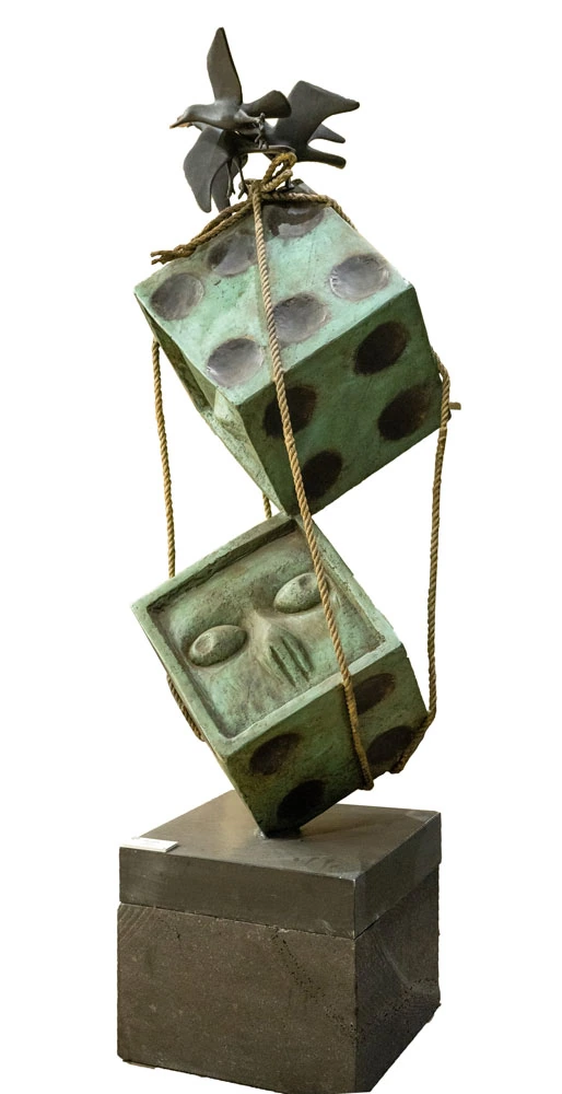 Two large bronze dice, one balanced on the other, bound together with rope, a bird alighting on the top.