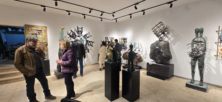 Visitors among the sculptures, with the twin figure beside the wall.