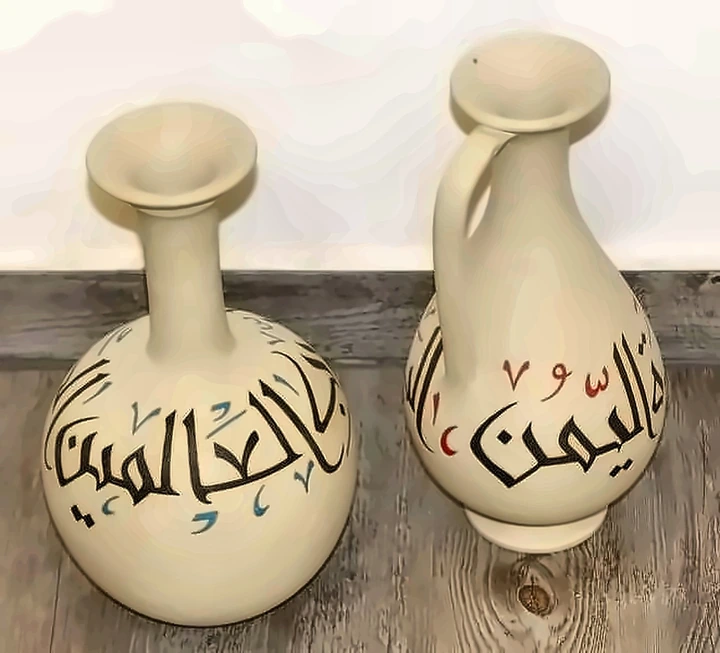 Two cream jars painted with Arabic calligraphy in black with blue and red vowel marks.