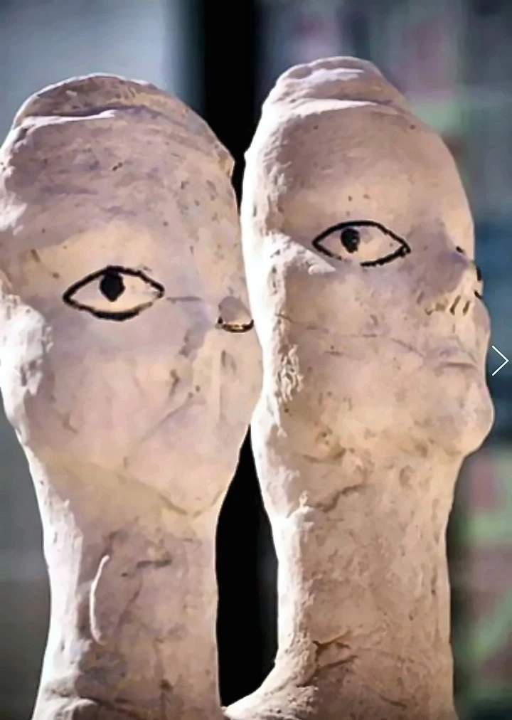 Two limestone figures side by side with painted eyes.