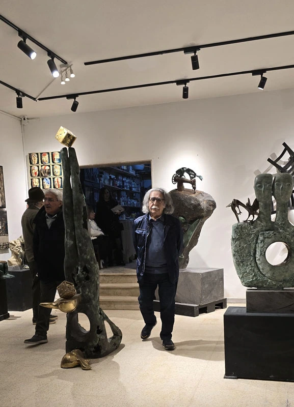 A bronze figure carrying birds in the hall, guests behind it.
