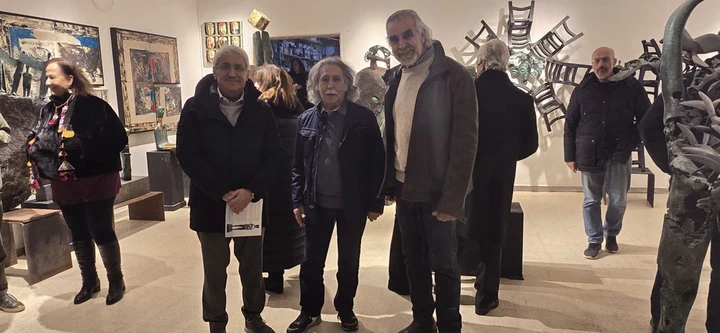Three men standing together in the gallery beside the works.