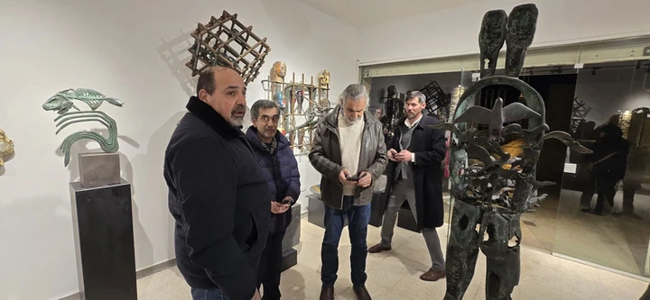 Guests standing beside a tall twin-headed bronze figure with birds.