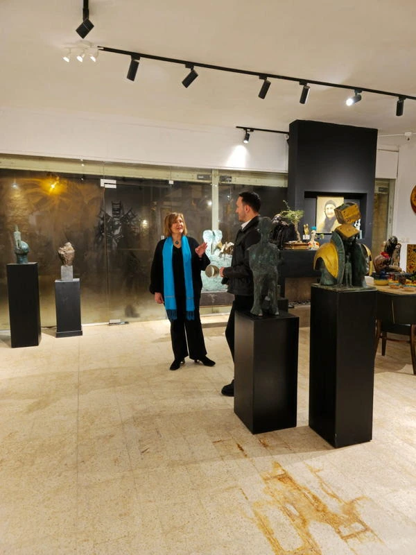 A visitor in a blue scarf between two bronzes.