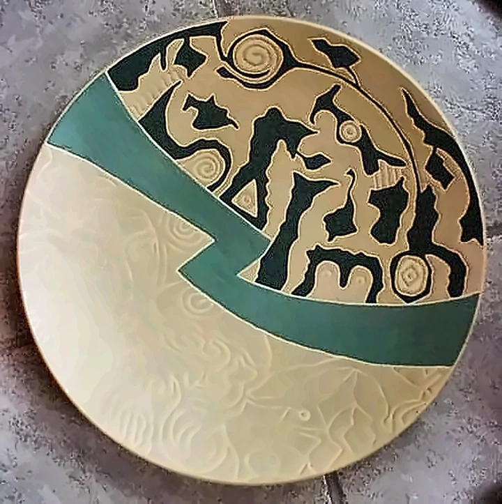 A cream plate crossed by a green band, one half incised with faint pattern, the other filled with dense black figures.