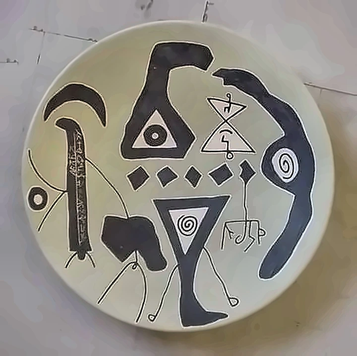 A pale plate with black hooks, triangles, spirals and a row of small diamonds.