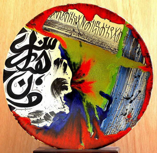 A plate where black calligraphy sits over poured red, green and blue that has run together.