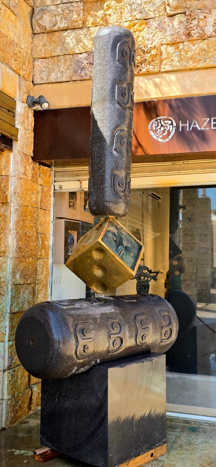 Three-quarter daylight view of the basalt cylinders and bronze cube outside the gallery door.
